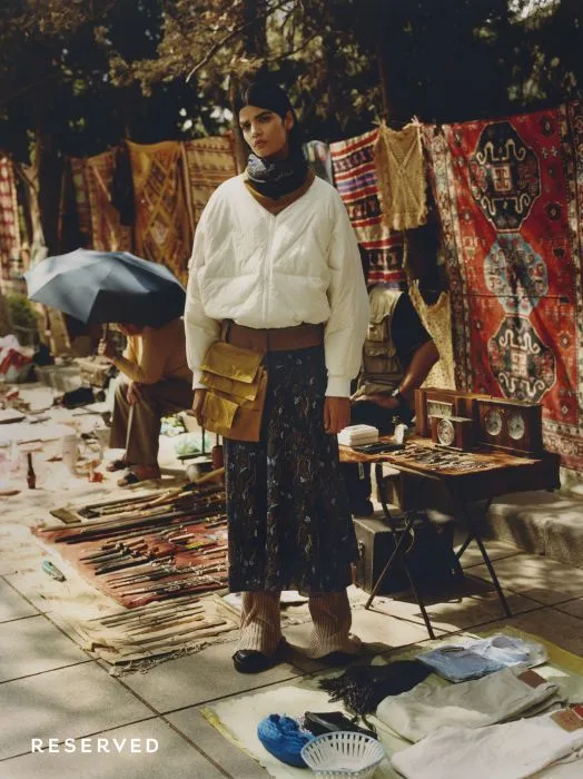 Model in a white blouse and printed skirt at a market