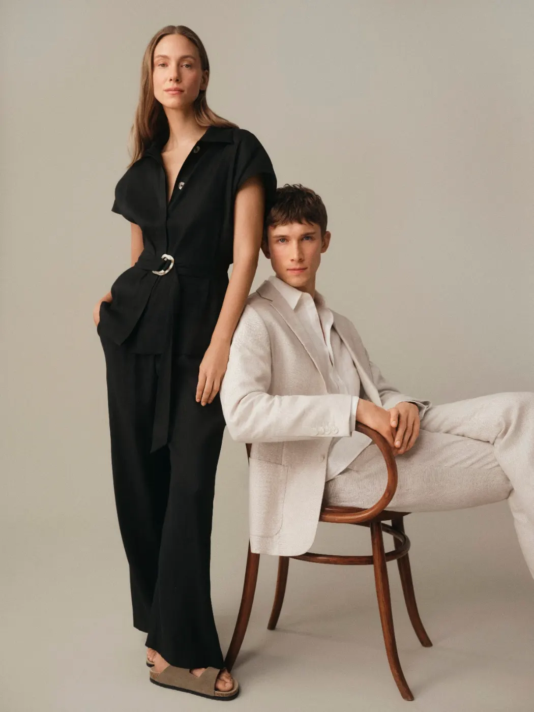 Two models in black and cream tailoring, seated and standing