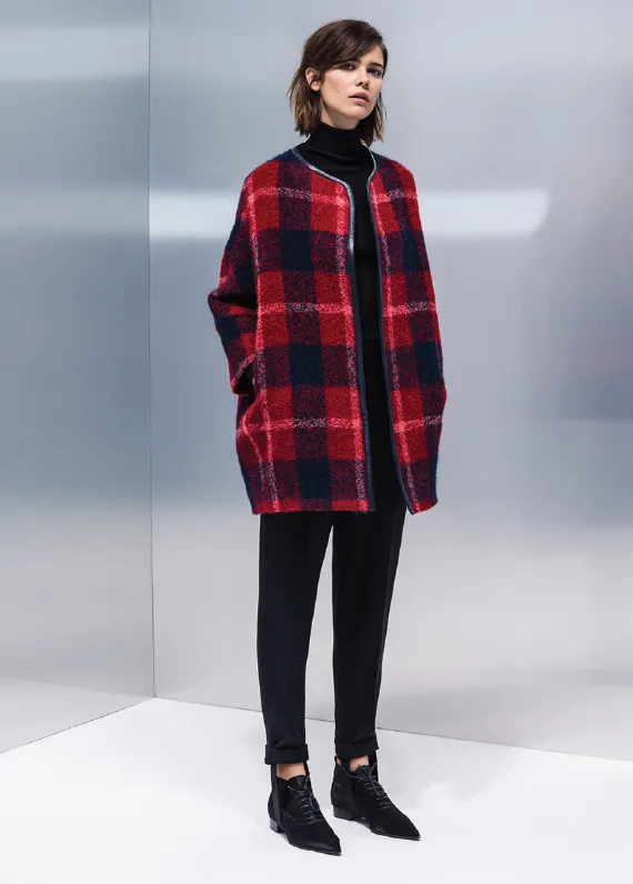 Model in a red and navy check coat on a grey background